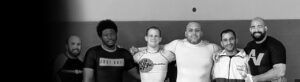 Six men smiling and posing with their arms around each other