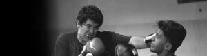 A man striking another man in the head with boxing gloves