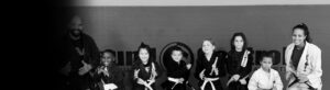 Line of kids and instructors posing in martial arts uniforms