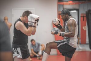 Two men in a muay thai class fighting each other