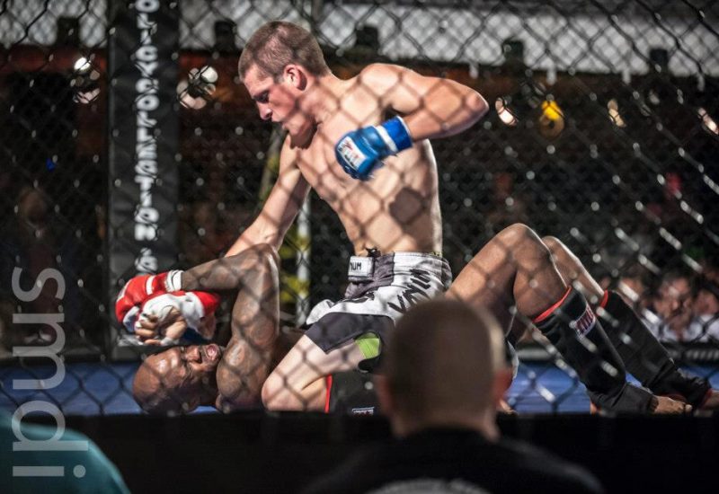 Shirtless man punching another man in an MMA ring